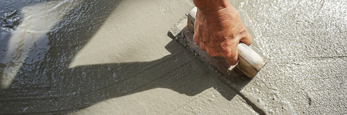 Man smoothing concrete surface with trowel.